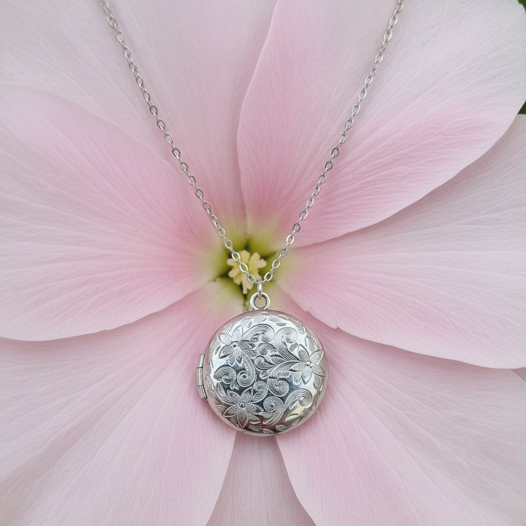 Silver necklace with a round patterned locket on a large flower