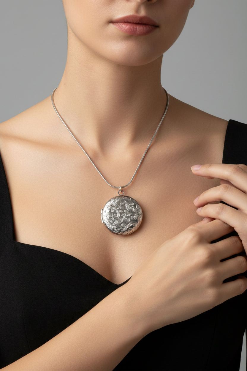 Silver necklace with a round patterned locket on a model