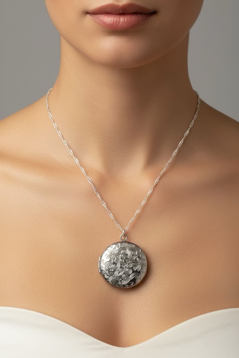 Silver necklace with a round patterned locket on a model against a neutral background