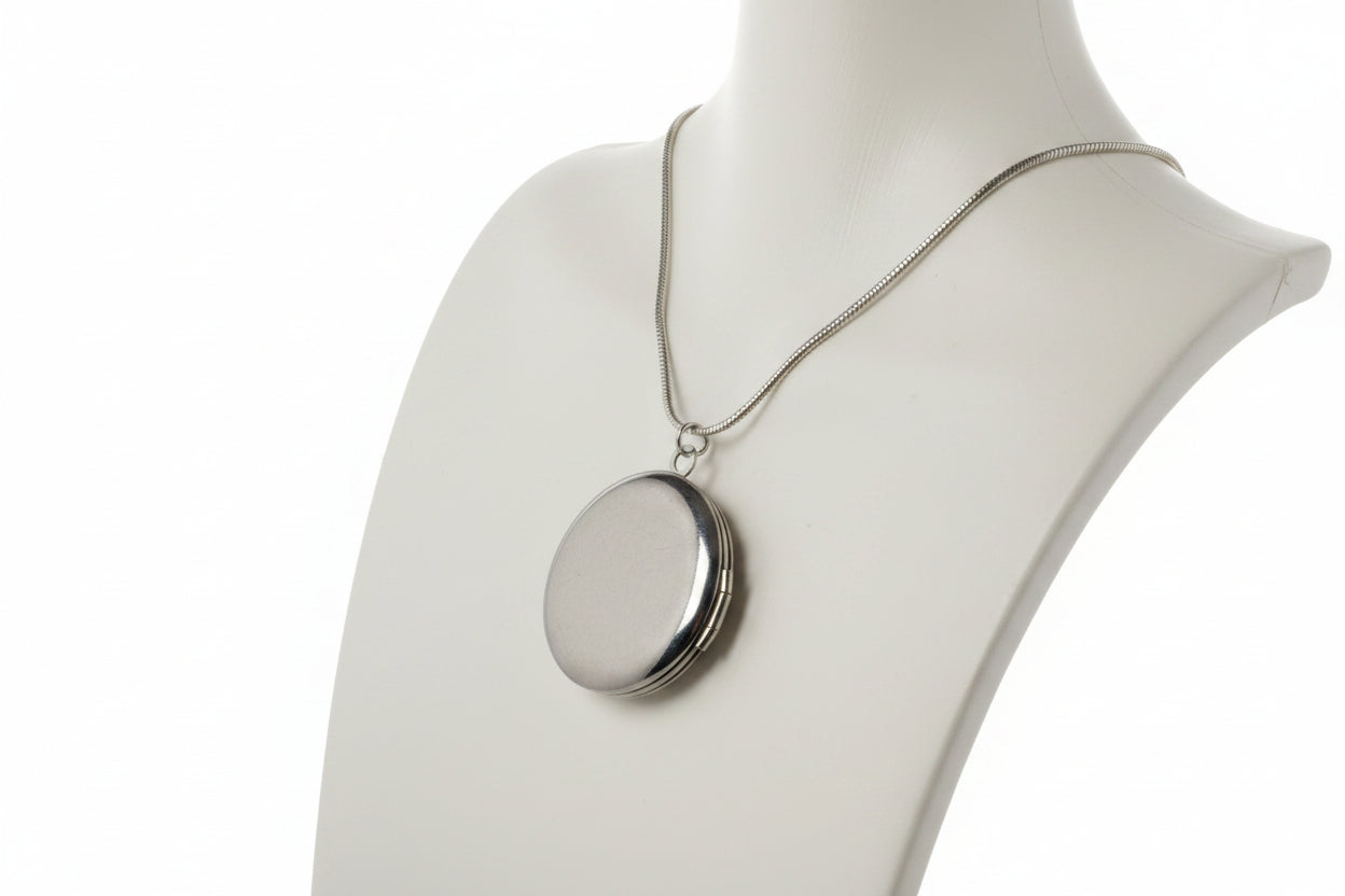 Silver necklace with a round locket on a mannequin bust.