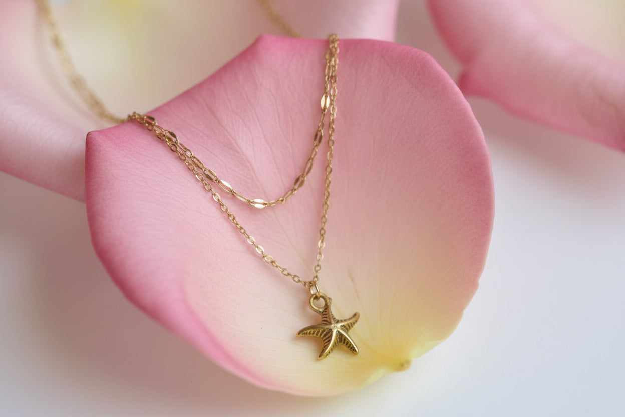 Gold chain necklace with a starfish pendant on a large rose petal 