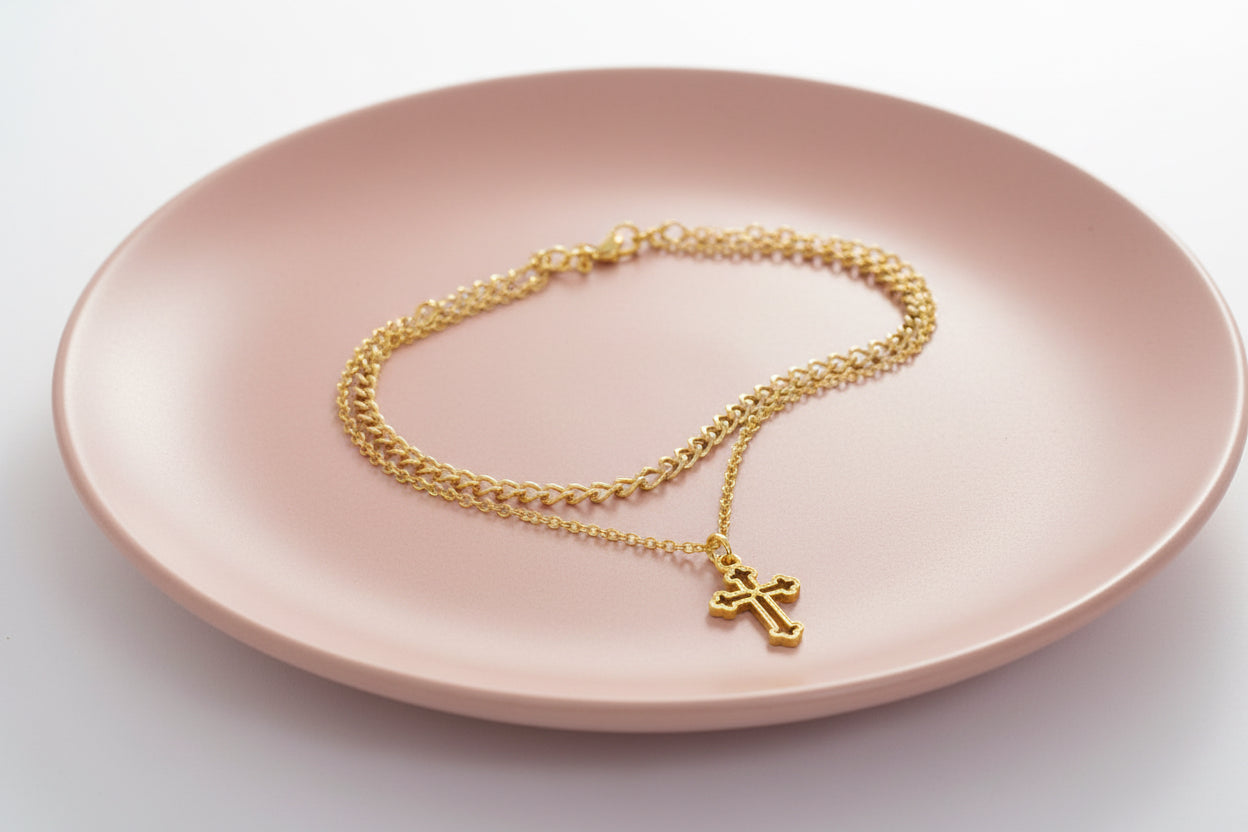 Gold chain necklace with a cross pendant on a large rose plate