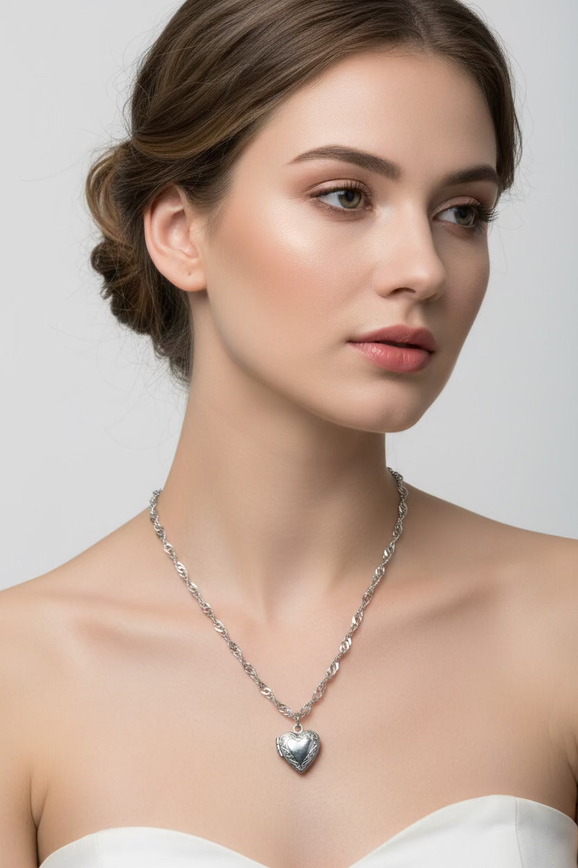 Woman wearing a silver water wave necklace with a heart locket against a plain background