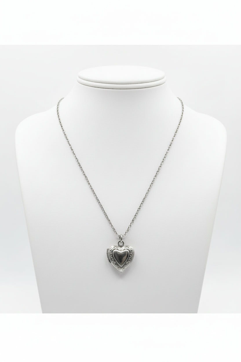 Stainless steel heart-shaped locket on chain link sterling silver necklace on a mannequin