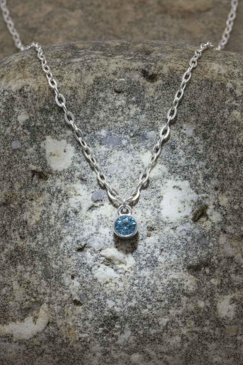 Silver necklace with a blue march birthstone pendant on a large brown stone