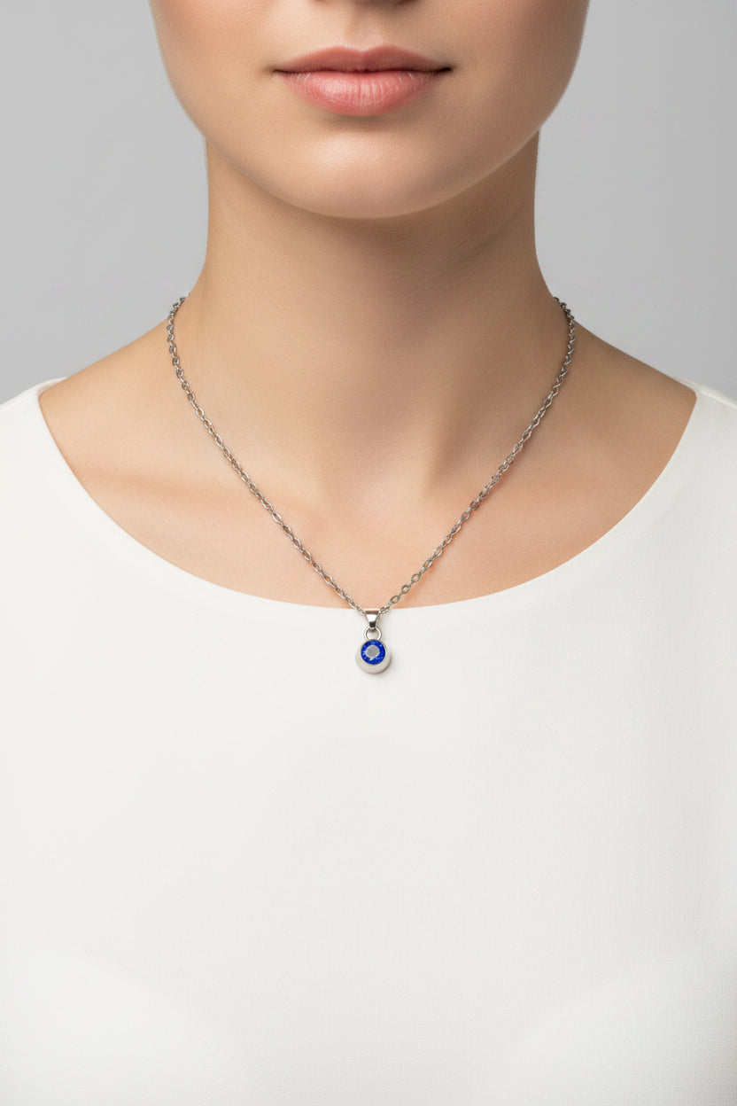 Silver necklace with a blue birthstone pendant on a model