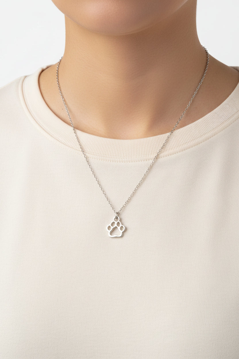 Silver necklace with a paw print pendant on a plain background