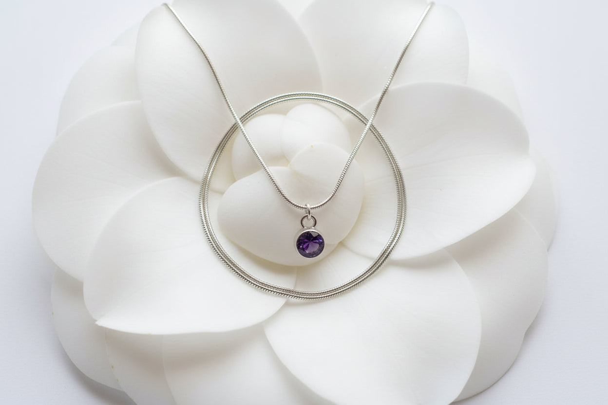 Necklace with a purple gemstone birthstone pendant on a large white petal