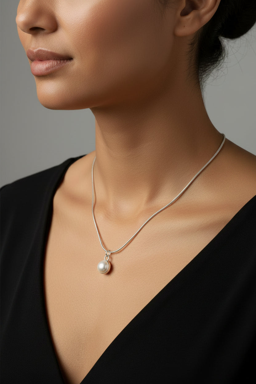 Silver necklace with a pearl pendant on a model.