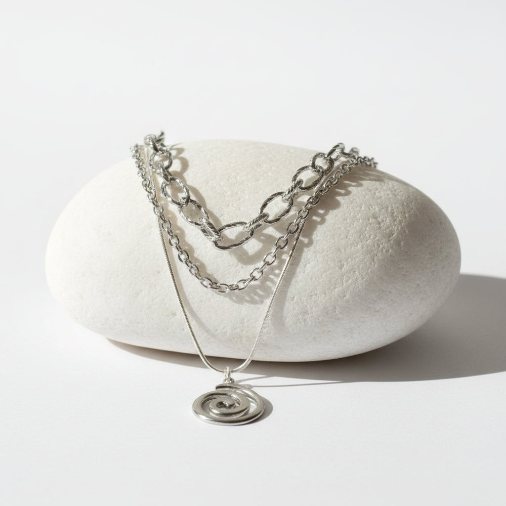 Triple silver necklace set with a prominent spiral pendant on a large white stone