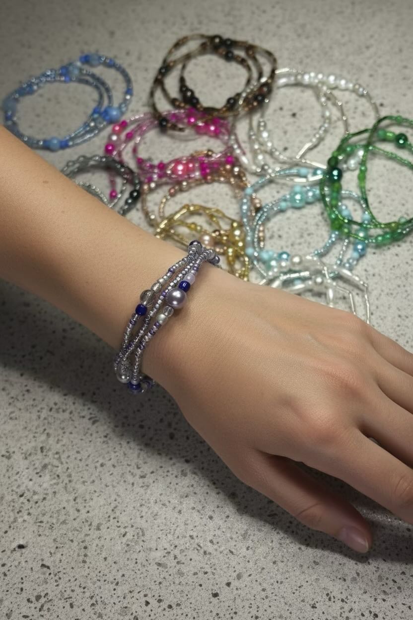 Hand wearing a bracelet with other bracelets on a speckled surface
