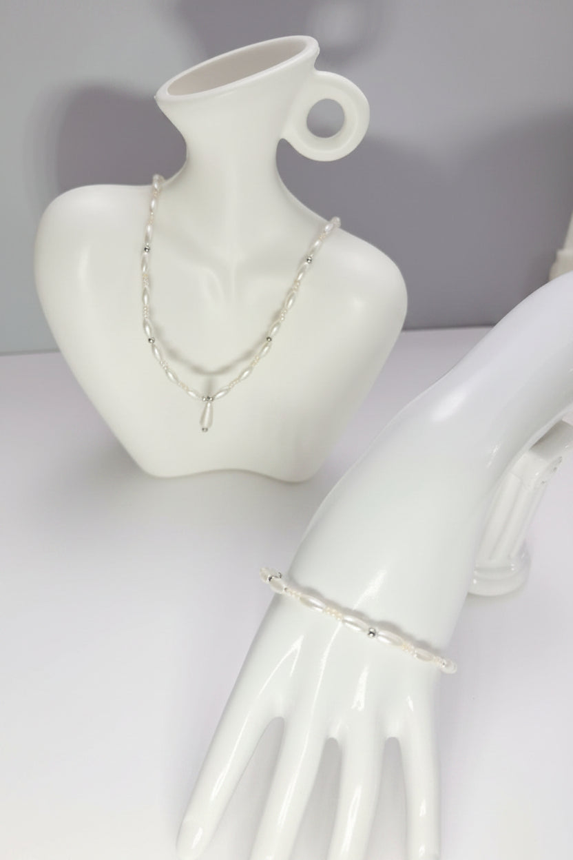 White ceramic mannequin with jewelry set on a plain background