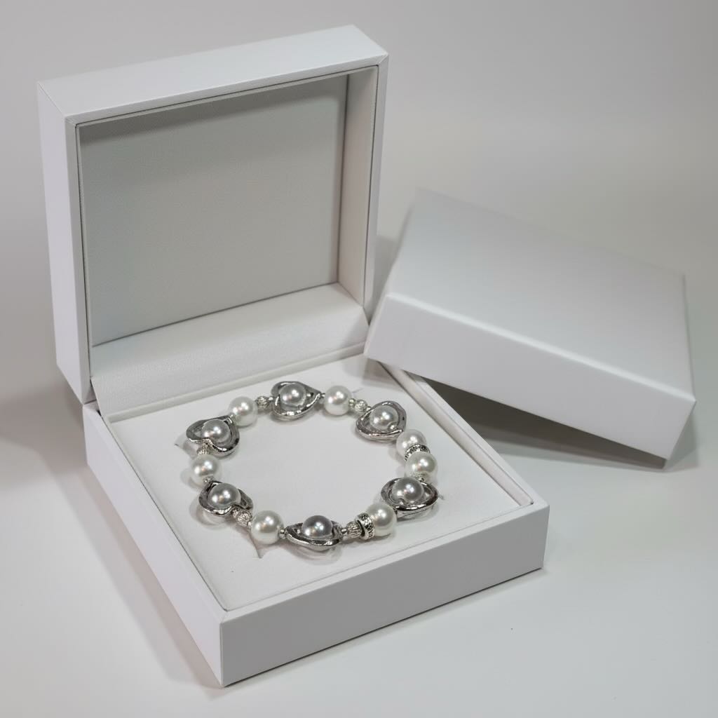 Silver and pearl bracelet in an open white jewelry box on a light gray background