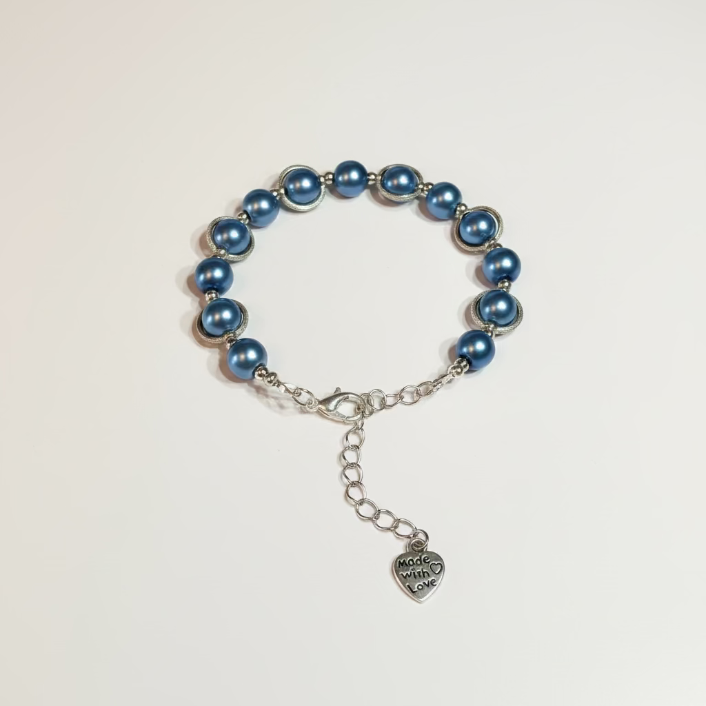 A beaded bracelet with teal blue pearls and silver-toned metal links, featuring a lobster clasp, extension chain, and a heart-shaped charm engraved with 'Made with Love'.