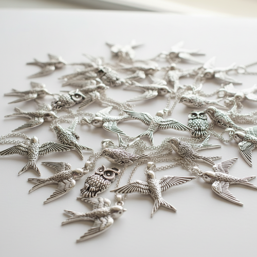 Silver bird shaped pendants on a white surface