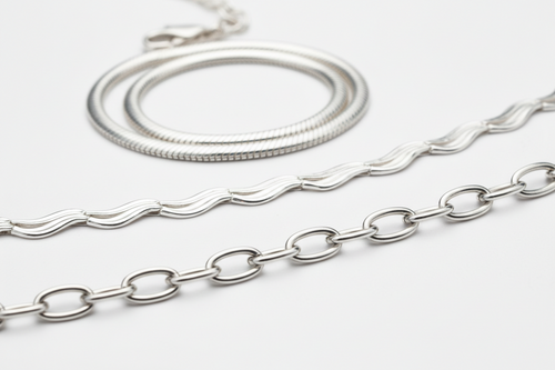 Two silver necklaces on a light gray background