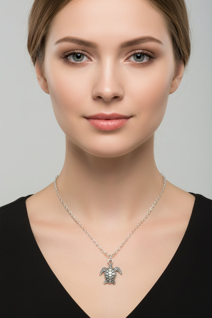 Silver turtle pendant necklace on a model with a plain background